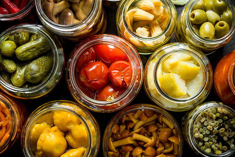 Various canned goods lined up next to each other. Various vegetables are in the cans.